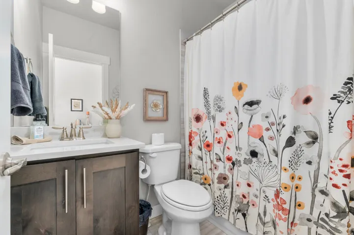 Full bathroom featuring a wood-finish vanity with a white countertop and integrated sink, brushed nickel faucet, and overhead vanity lighting