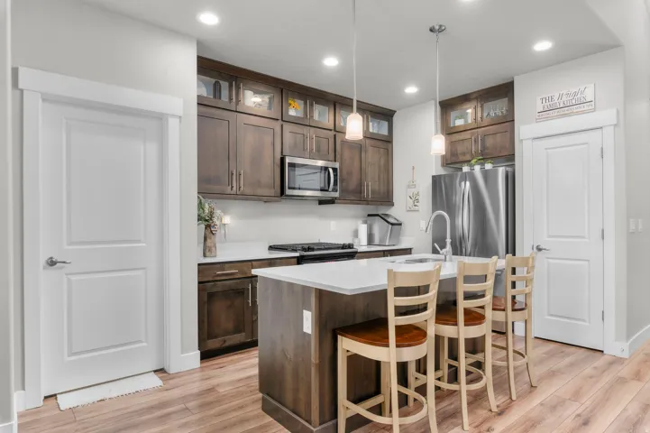 Modern kitchen featuring wood-finish flooring, white countertops, and dark wood cabinetry