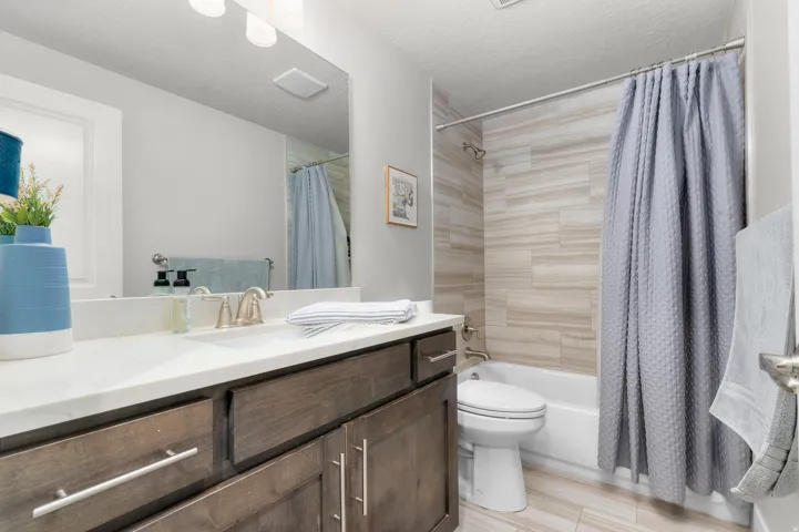 Bathroom featuring a wood-finish vanity with a white countertop and undermount sink, brushed nickel faucet, and a large wall-mounted mirror
