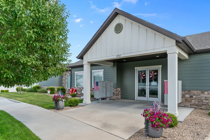 Covered entryway featuring double glass-paneled doors, vertical board and batten siding, and stone accents