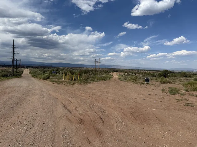 Expansive open land featuring a dirt road, sparse vegetation, and distant mountains