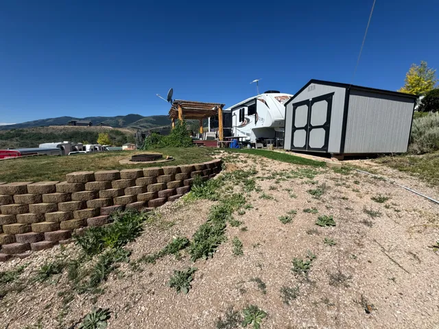 Terraced retaining wall leading to a flat, grassy area with a built-in fire pit