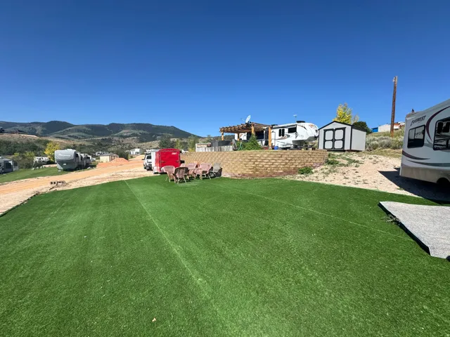 Expansive artificial turf lawn with a brick retaining wall and mountain scenery
