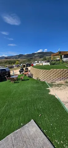 Expansive outdoor space featuring artificial turf, a stone retaining wall, and mountain backdrops