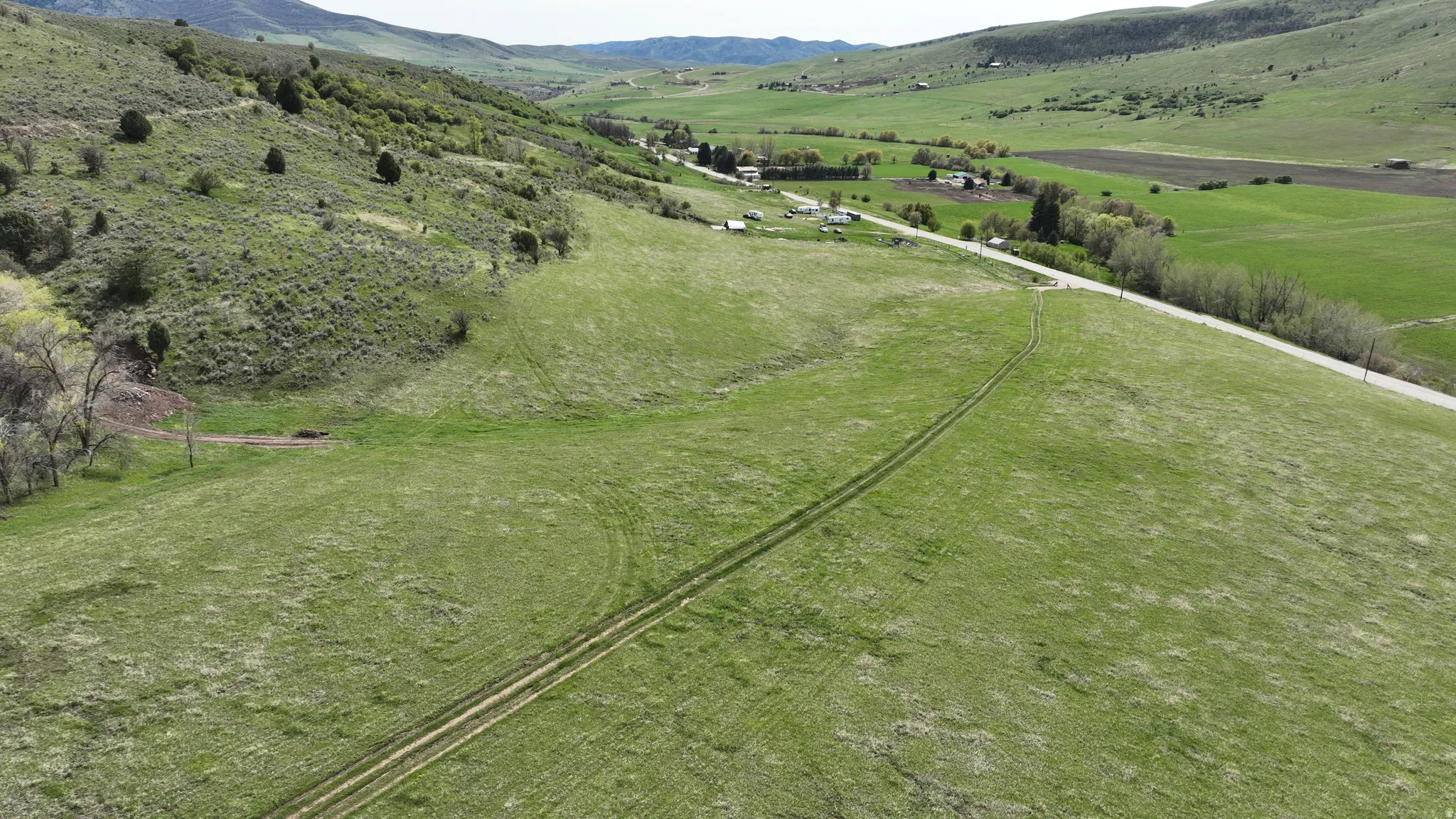 Expansive green terrain with a visible track, bordered by a paved road