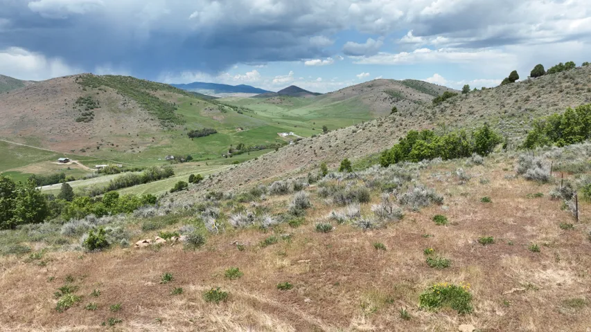 Expansive hillside property featuring varied terrain, natural vegetation, and distant mountain ranges