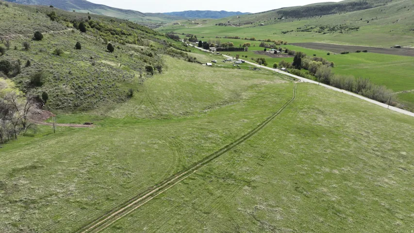 Expansive green terrain with a visible track, bordered by a paved road