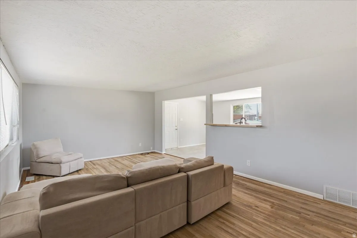 Spacious living area featuring wood-finish flooring, light gray walls, and white trim