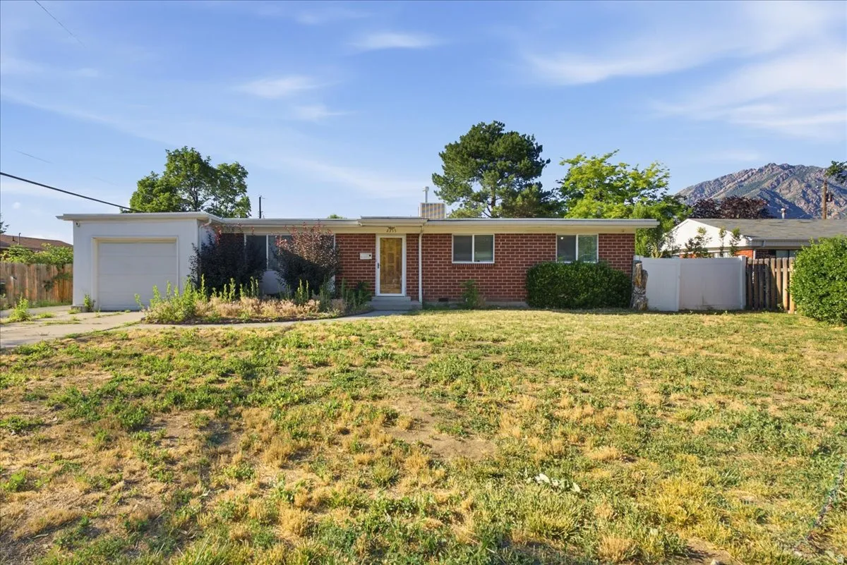 Single-story residence featuring a brick facade with a prominent front lawn