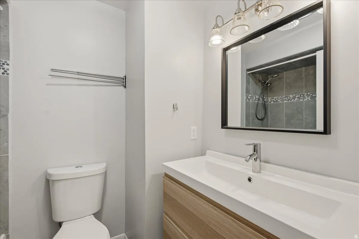 Modern bathroom featuring a wood-finish vanity with an integrated white sink, a framed mirror, and a wall-mounted light fixture