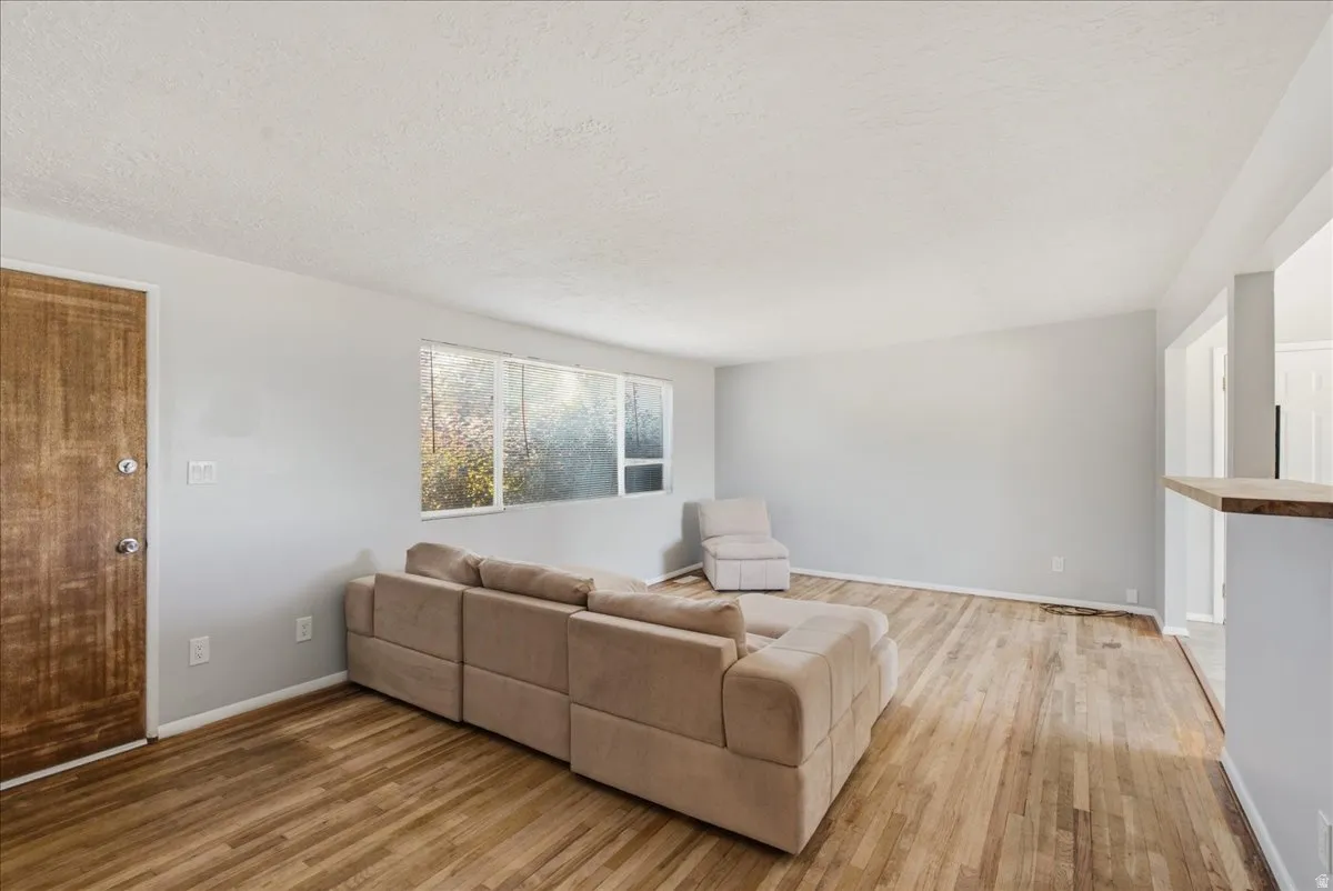 Spacious room featuring wood-finish flooring, a window offering exterior views, and a half-wall partition