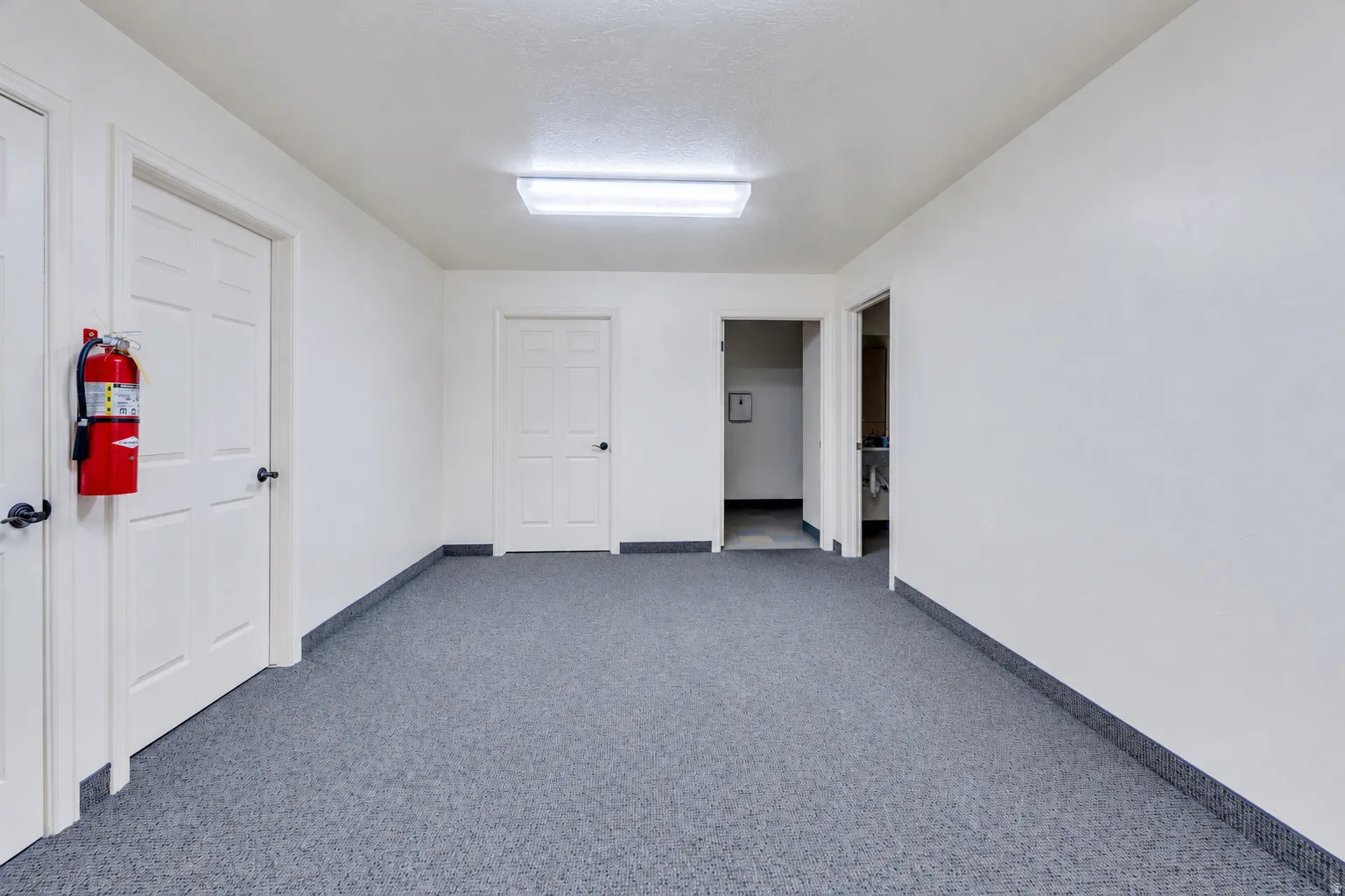 Spacious interior room with gray carpet flooring and white painted walls