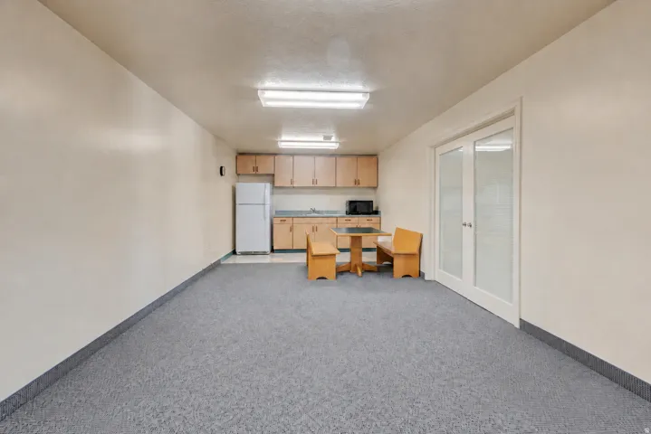 Open-plan area featuring light-toned walls, gray patterned carpeting, and white baseboards