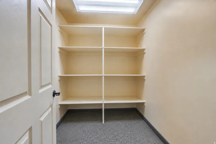 Built-in shelving unit providing extensive storage, neutral wall tones, overhead fluorescent lighting, and a durable speckled floor