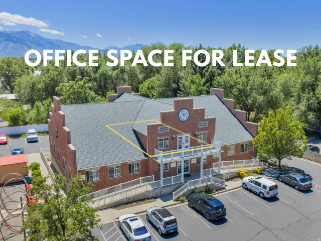 Brick commercial building featuring gabled rooflines, a prominent exterior clock, and multiple parking areas