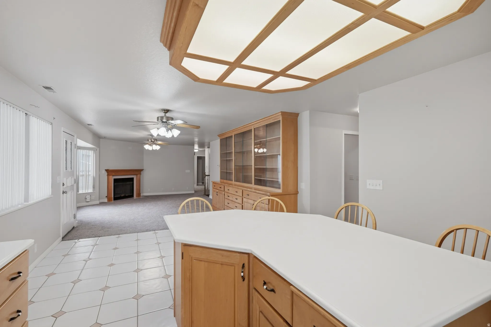 Kitchen island with light wood cabinetry, a solid surface countertop, and bar seating