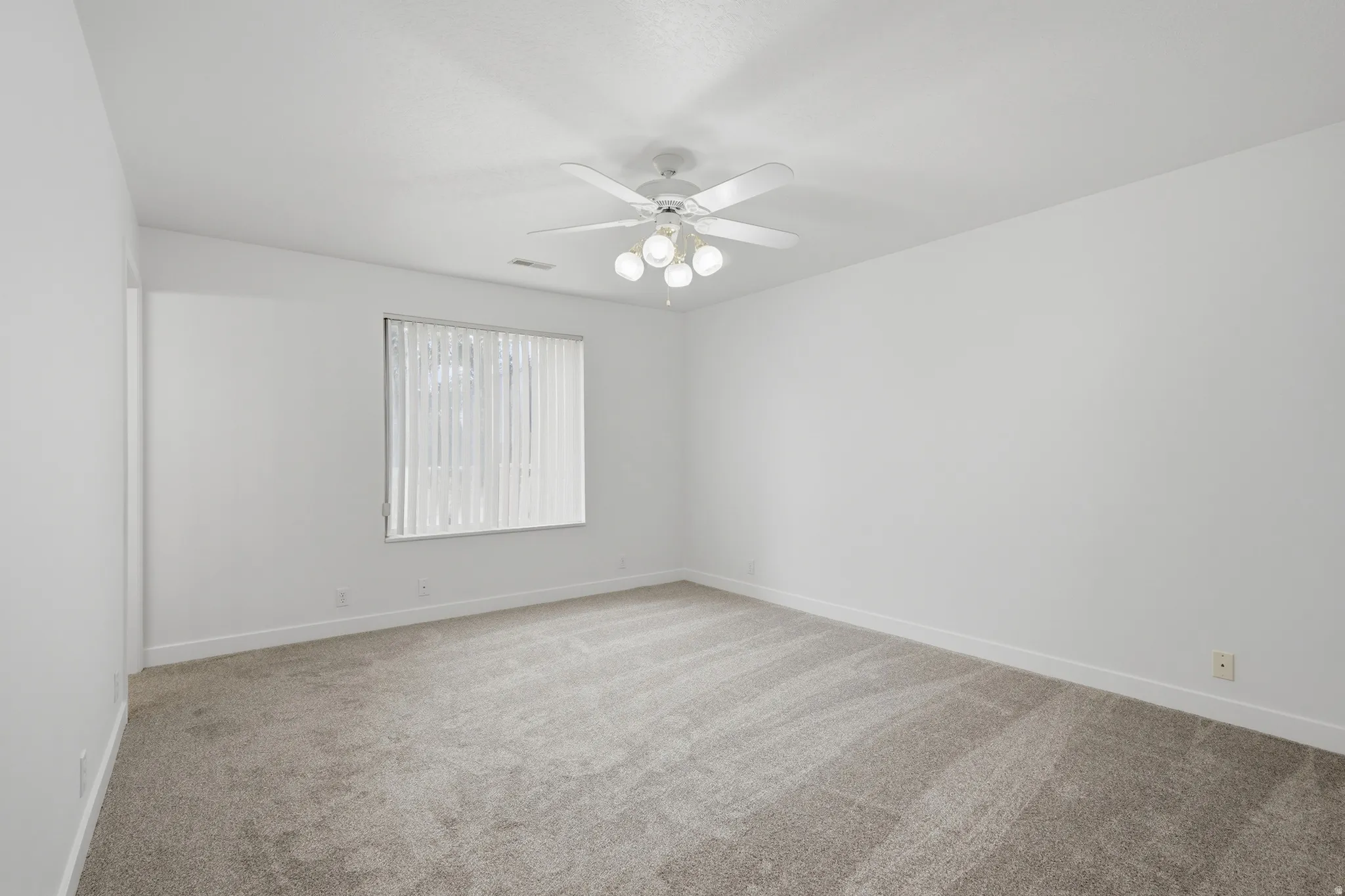 Spacious room featuring neutral carpeting and white walls