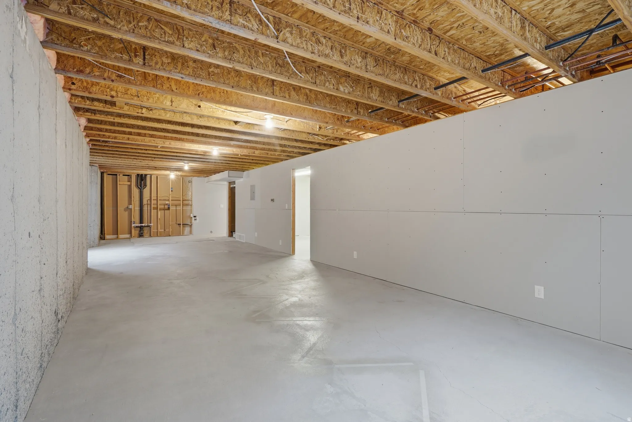 Unfinished basement featuring concrete flooring and exposed ceiling joists
