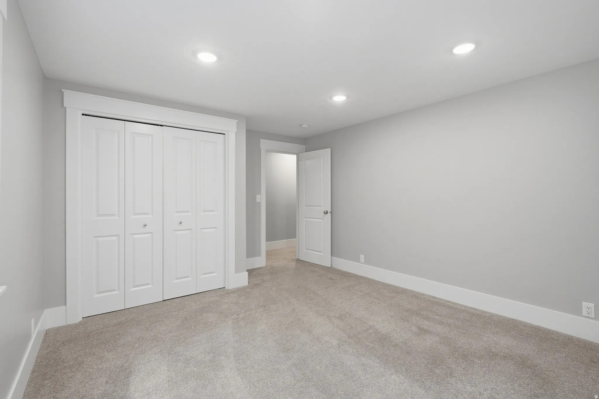 Spacious room featuring neutral carpeting, light gray wall tones, and white trim