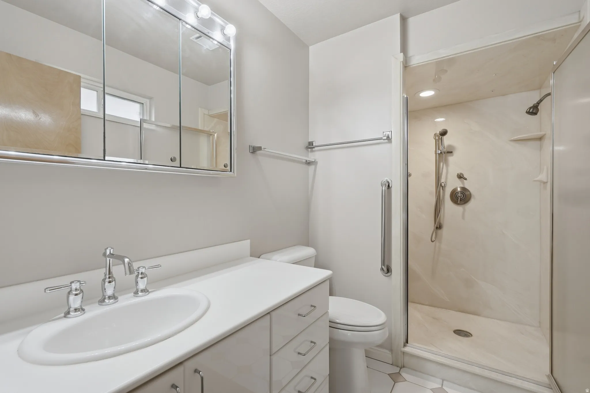 Primary bathroom featuring a white vanity with an integrated sink, polished chrome faucet, and a large mirrored medicine cabinet