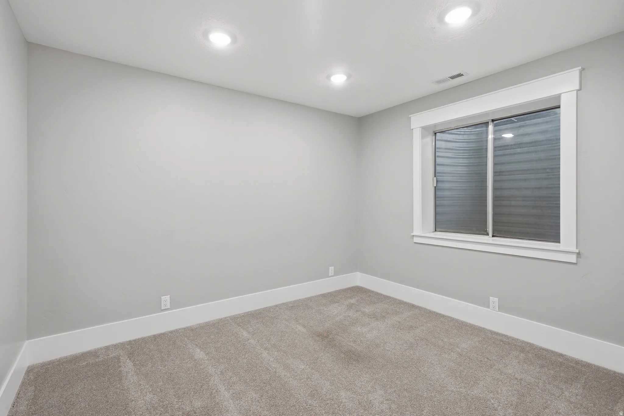 Neutral-toned room featuring light gray walls, recessed lighting, and soft carpet flooring