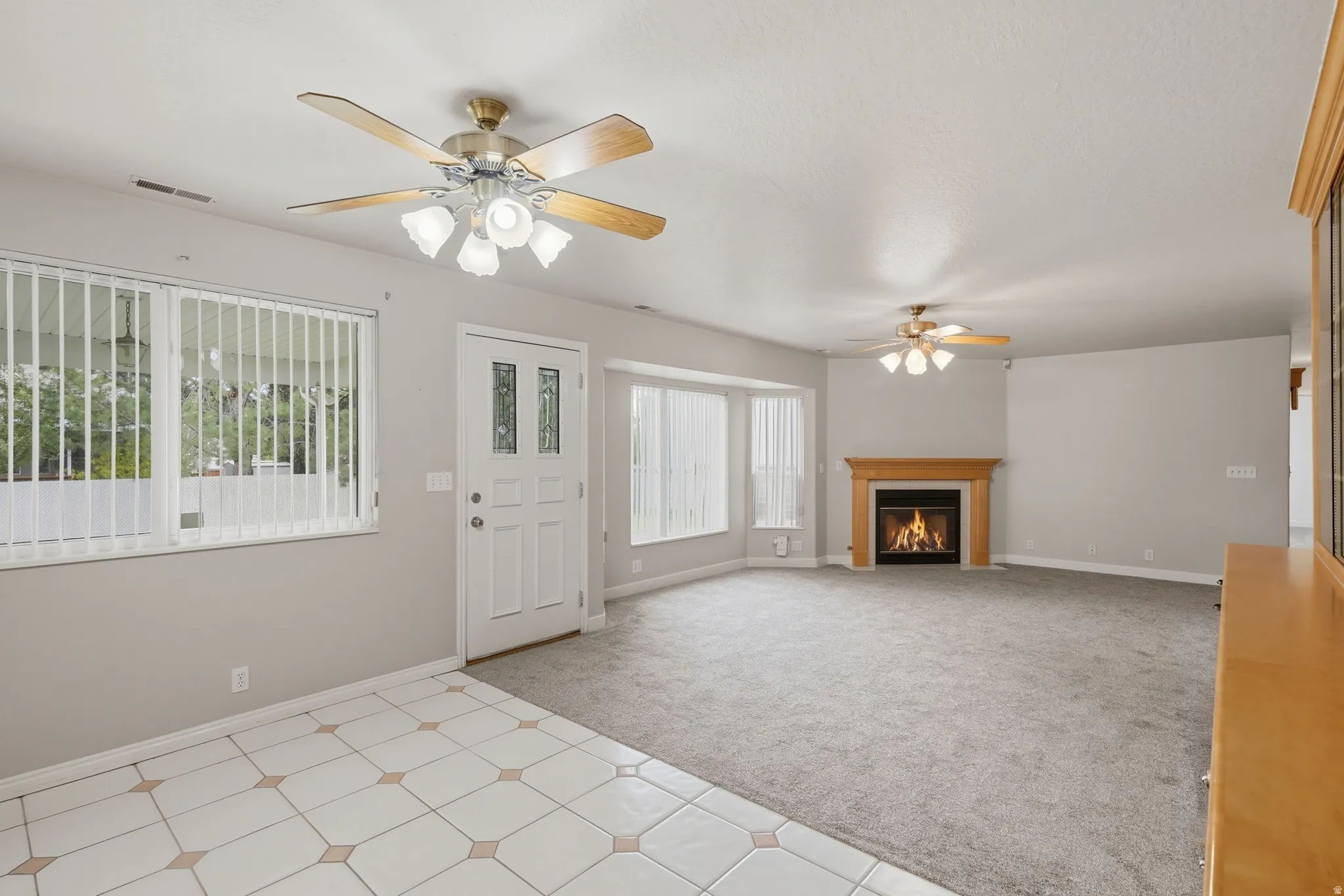 Living area featuring a fireplace with a wood mantle, bay windows, and carpet flooring