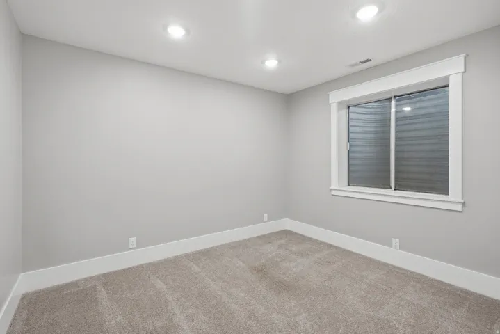 Neutral-toned room featuring light gray walls, recessed lighting, and soft carpet flooring