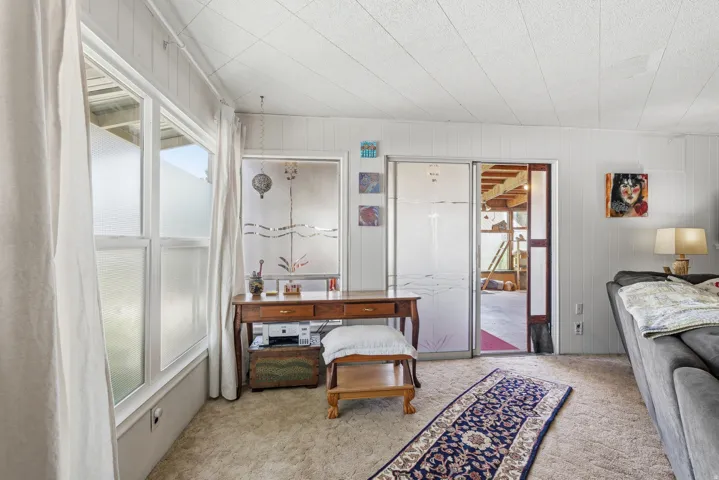 Carpeted room featuring white paneled walls and a white textured ceiling