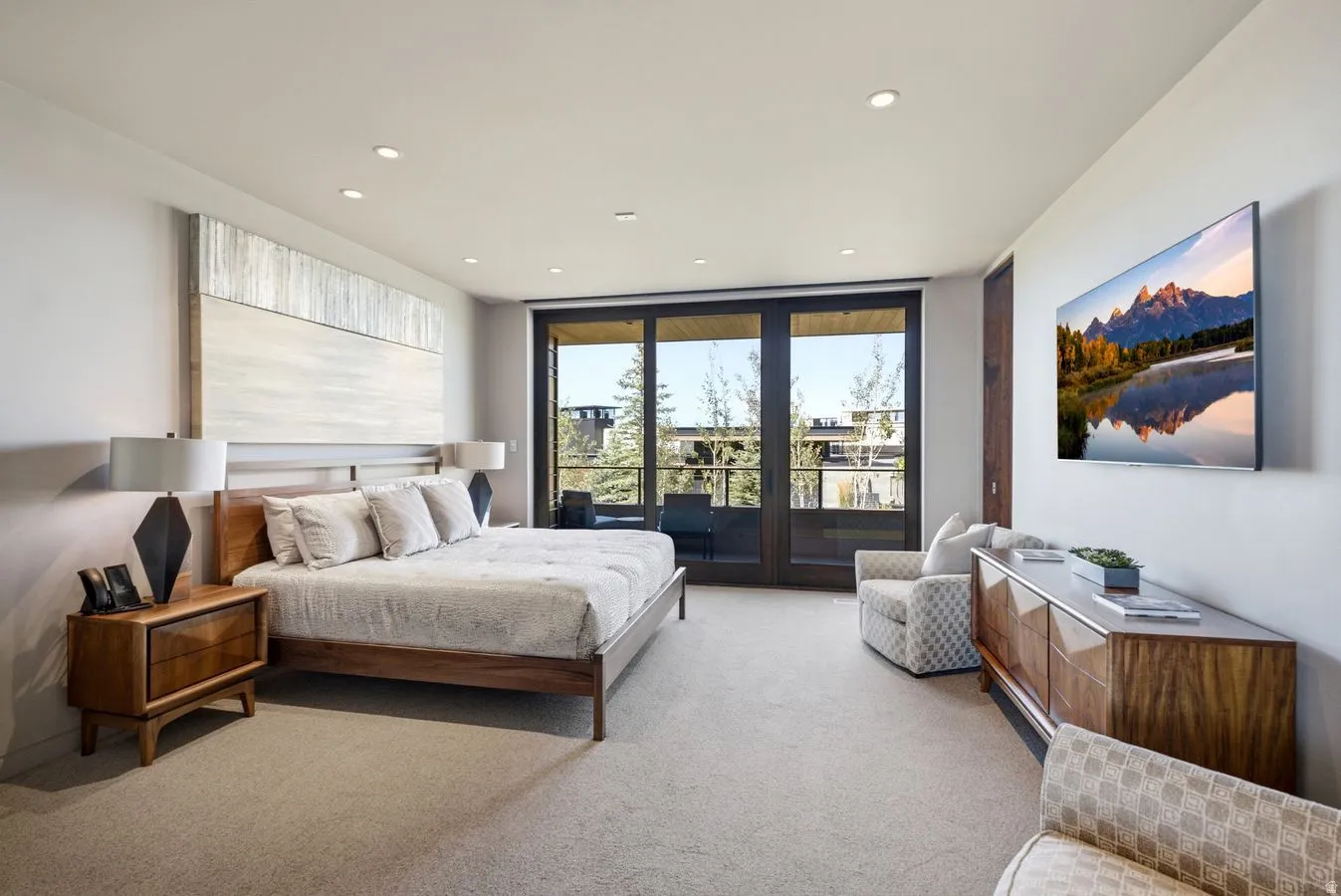 Recessed lighting, light-toned carpeting, dark wood-framed glass doors, and a wall-mounted display