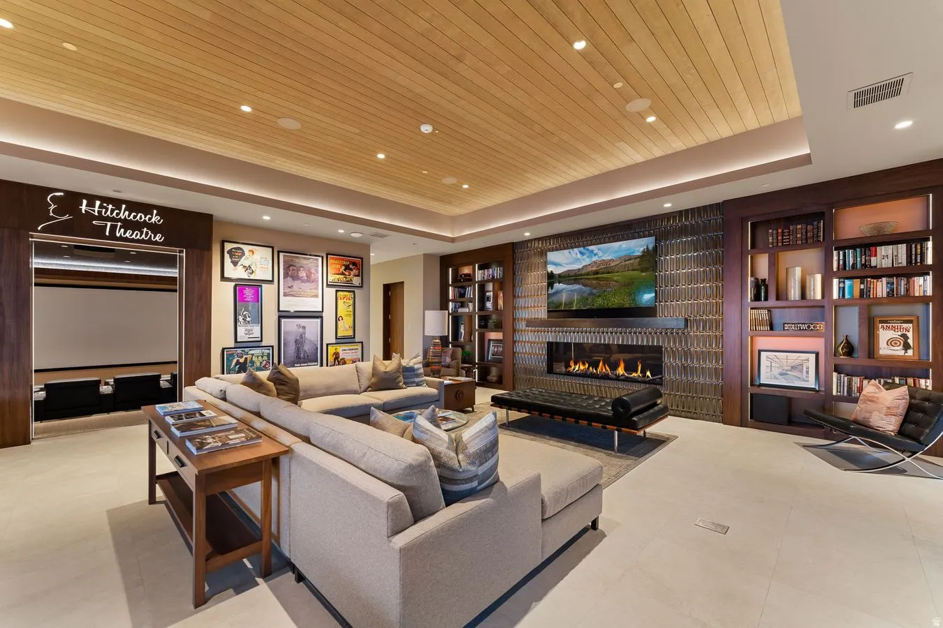 Media room featuring a built-in projection screen, wood-paneled ceiling, integrated linear fireplace, and built-in shelving