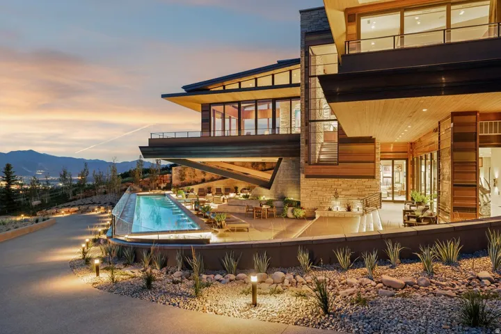 Modern multi-level exterior with extensive glazing, wood-paneling, and natural stone accents