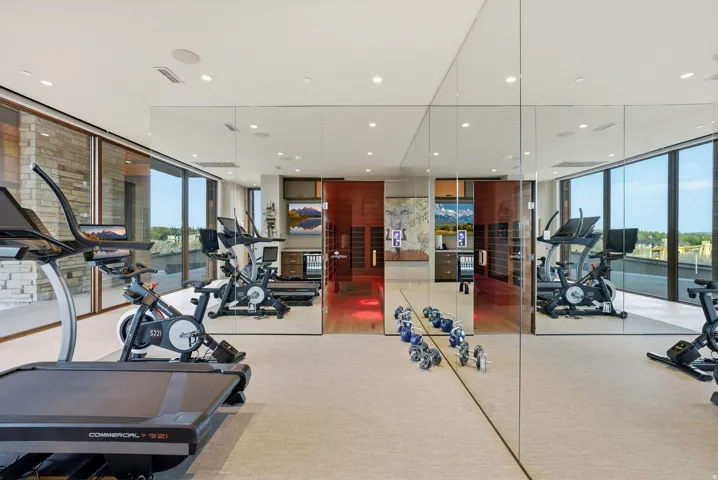 Expansive room with floor-to-ceiling windows, mirrored wall, recessed lighting, and light-toned carpeting