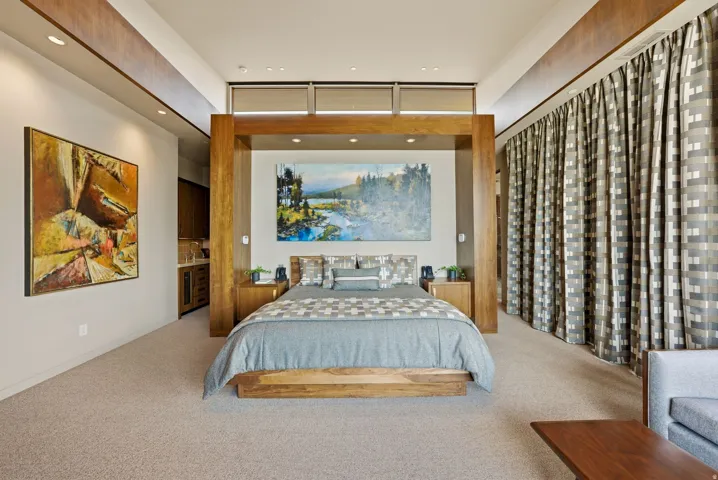 Recessed lighting, wood-finish architectural details, integrated wet bar with built-in cabinetry, full-height window treatments, and carpeted flooring