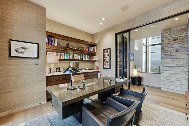 Recessed lighting, wood-finish flooring, built-in shelving, stone accent wall, and sliding glass panel doors