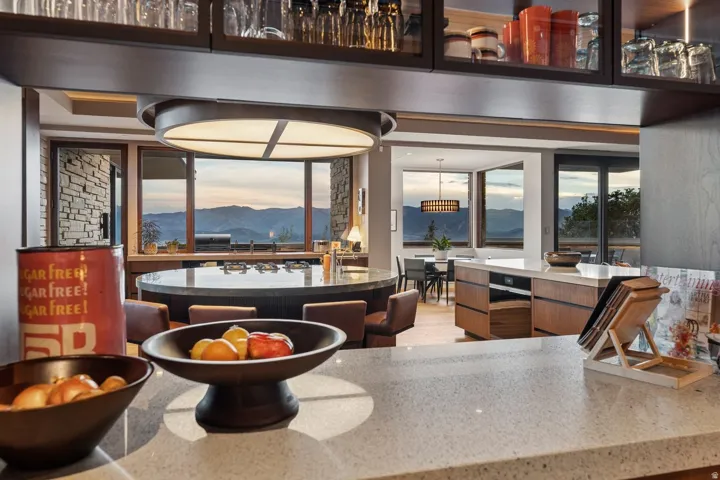 Quartz countertop, custom cabinetry, large windows, mountain scenery, and stone accent wall
