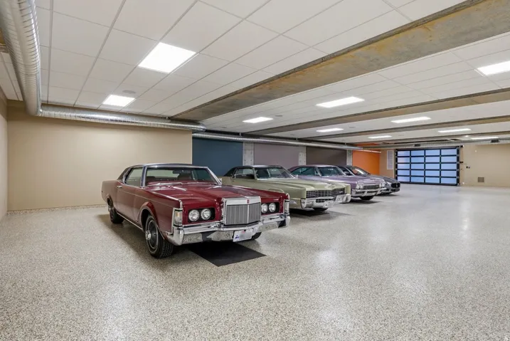 Spacious garage featuring a durable epoxy floor, exposed ductwork, drop ceiling with integrated lighting, and a modern glass garage door