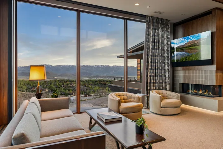 Floor-to-ceiling windows, wood-paneled accent wall, built-in linear fireplace, integrated media display, and recessed lighting