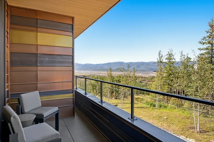 Expansive outdoor balcony with a glass railing system and a wood-finish ceiling