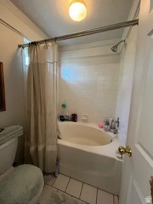 Bathroom featuring a white subway tile tub surround, white bathtub, chrome shower fixtures, and a flush mount ceiling light