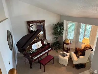 Vaulted ceiling room featuring a large bay window with plantation shutters