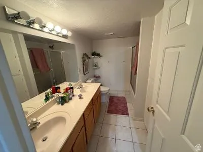 Bathroom with dual vanity featuring integrated sinks, light-toned countertops, and wood-finish cabinetry