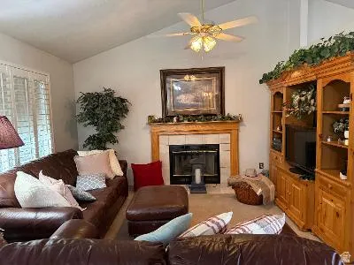 Living room featuring a vaulted ceiling and a ceiling fan with integrated lighting