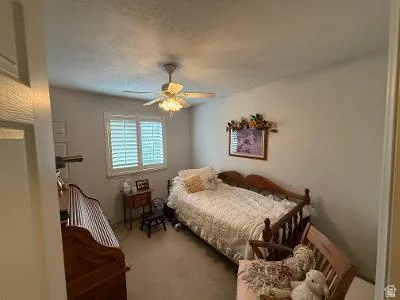 Bedroom featuring a window with white louvered shutters, a ceiling fan with integrated lighting, and neutral wall tones