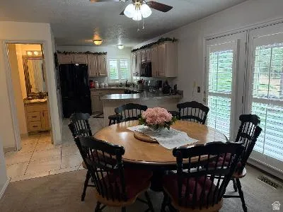 Open-concept kitchen and dining area featuring light-toned cabinetry, dark appliances, and a central island with a breakfast bar