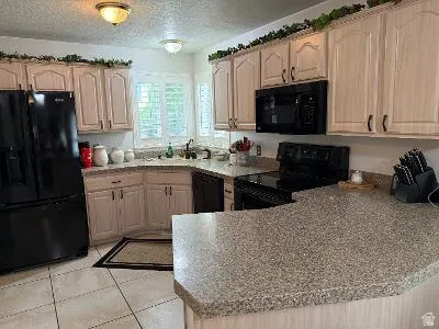 Kitchen featuring light-toned cabinetry, a black appliance suite, and speckled countertops