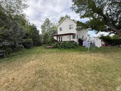 Expansive rear yard featuring mature trees, a multi-level deck with a pergola, and a visible hot tub