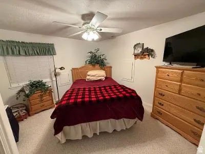 Bedroom featuring carpet flooring, a window with horizontal blinds, and a ceiling fan with integrated lighting