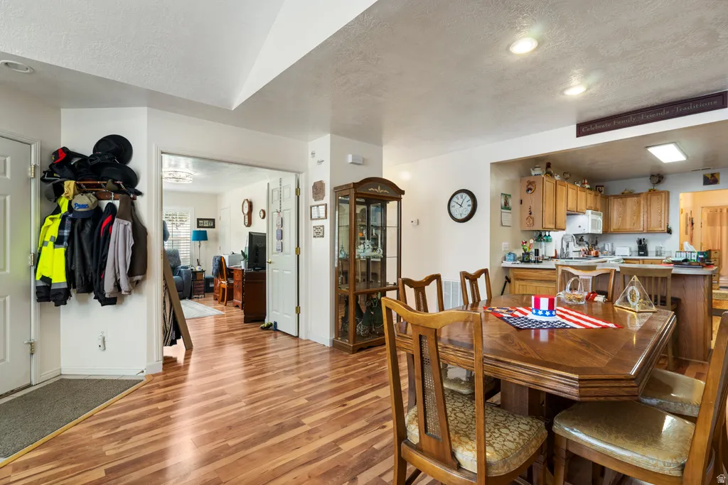 Hardwood-finish flooring throughout, featuring a kitchen with wood cabinetry and white appliances, and a dining area