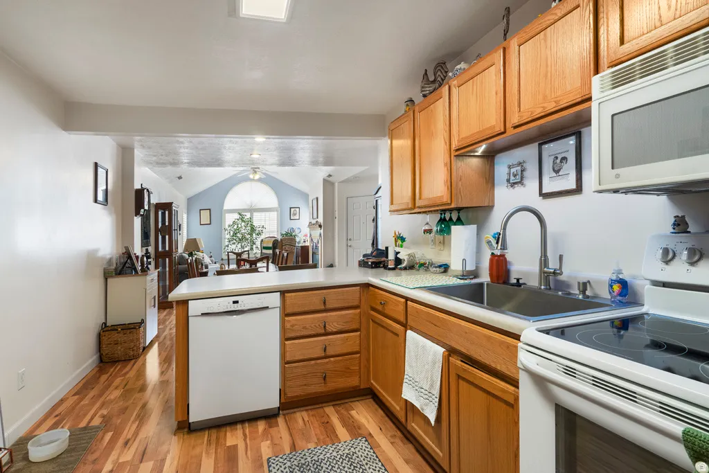 Kitchen featuring wood-finish flooring, light-toned cabinetry, light countertops, and a stainless steel sink with a modern faucet