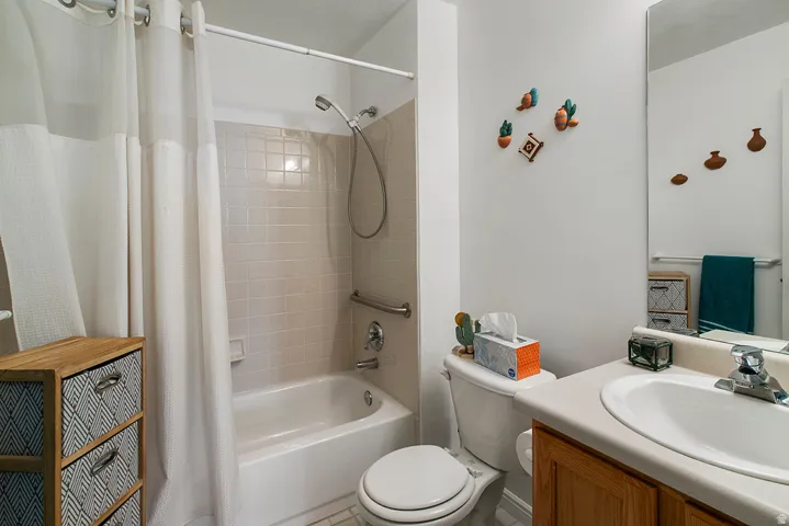 Bathroom featuring a white bathtub with subway tile surround, a built-in grab bar, and a showerhead with a handheld sprayer